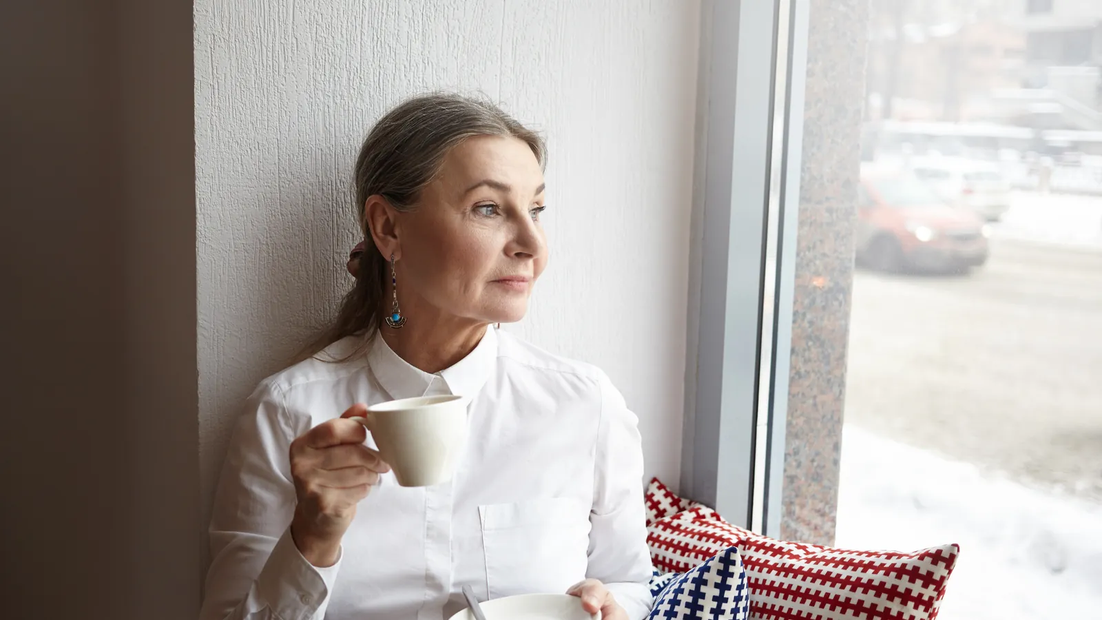 midlife crisis woman: a woman with a cup of coffee gazing out a window