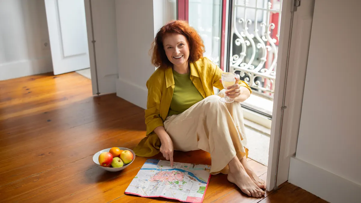 A woman in her forties sitting on the floor planning a route on a map