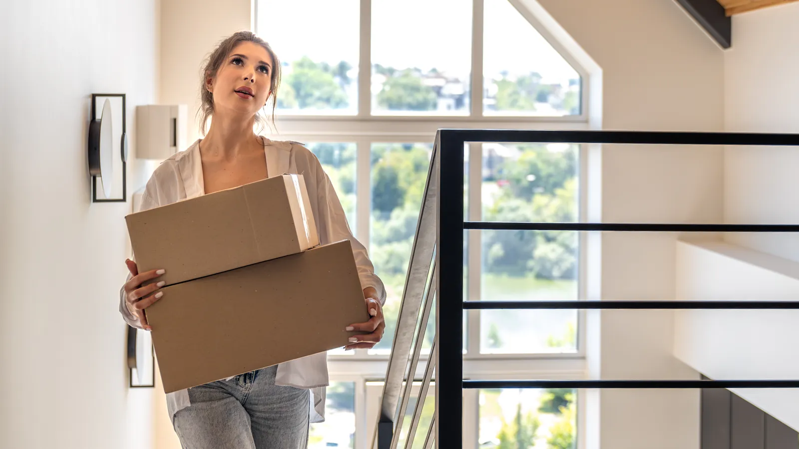 starting over at 30: a woman carrying moving boxes through a bright new home
